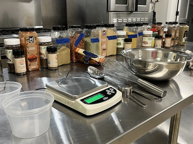 Commercial kitchen rental space at Adrian Armory with spices, prep tools, and stainless steel workstations.