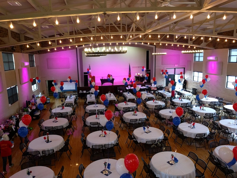 Inside photo of event hall with tables set and balloons for decorations