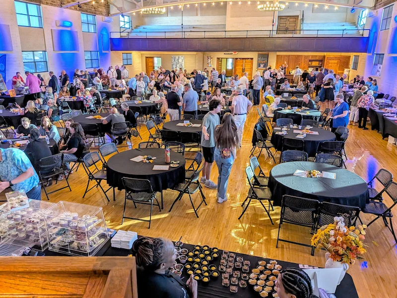 Vendor hall with tables showcasing food samples and patrons visiting tables for annual Taste of Lenawee Fundraiser Event at the Adrian Armory.