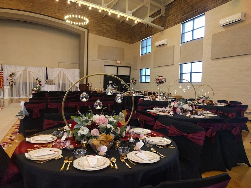 Catered wedding reception tables with floral décor at Adrian Armory Events Center.