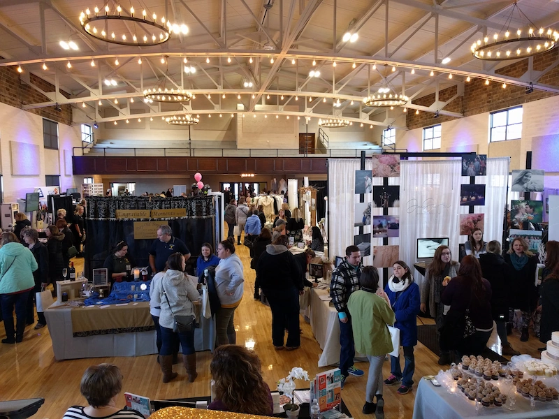 Wedding expo vendors and attendees inside Adrian Armory event hall in Adrian MI.