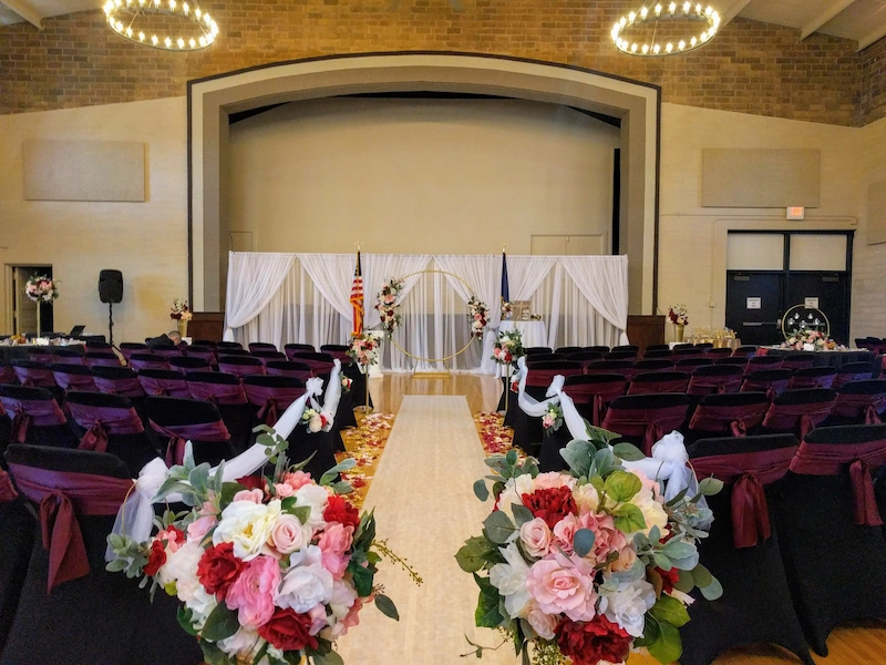 Wedding venue ceremony layout with floral aisle and stage backdrop at Adrian Armory Events Center.